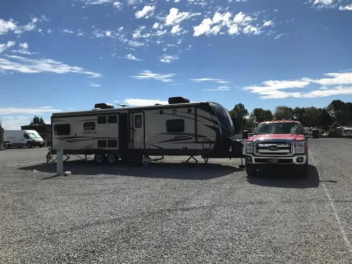 A travel trailer and pickup truck parked on a full-hookup pull-thru gravel site at Heartland RV Park in Campbellsville, KY